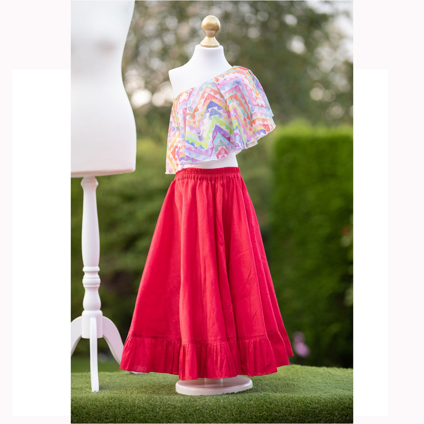 little girls into western outfit, a large oversized frill as a top and a bright red/pink skirt